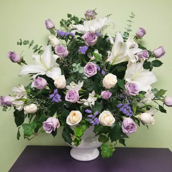 Lavender roses and white lilies arranged in a white vase