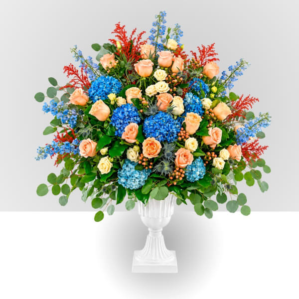 Large mixed floral arrangement in a white pedestal vase