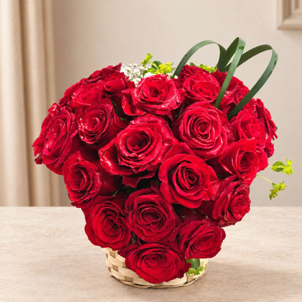 Basket of red roses with small white flowers and green accents