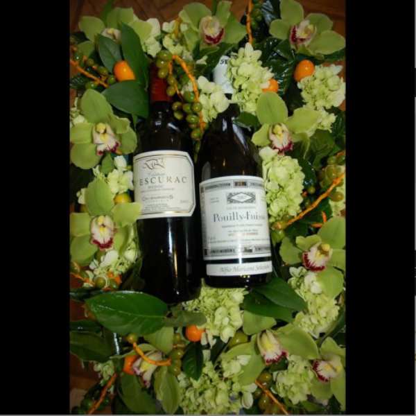 Wine bottles surrounded by green orchids and pale flowers