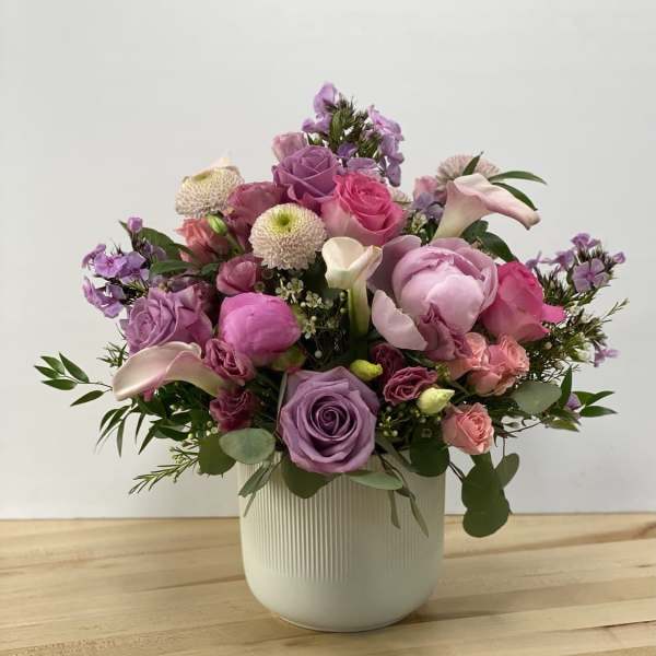 Mixed pink and purple flower arrangement in a white vase