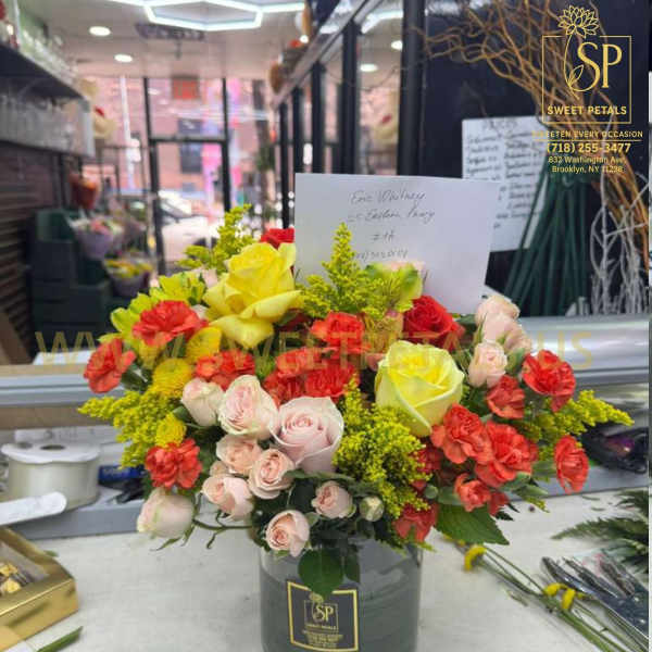 Mixed bouquet of yellow, pink, and red roses in a glass vase