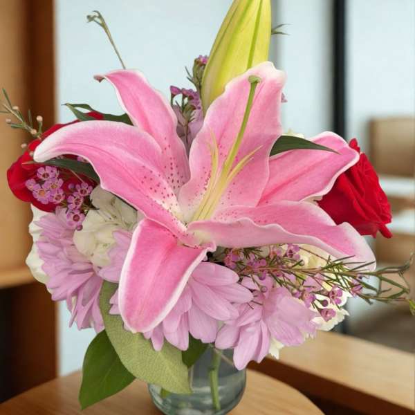 Pink lilies and red roses in a clear glass vase