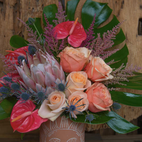 Bouquet of peach roses and pink anthuriums in a terracotta vase