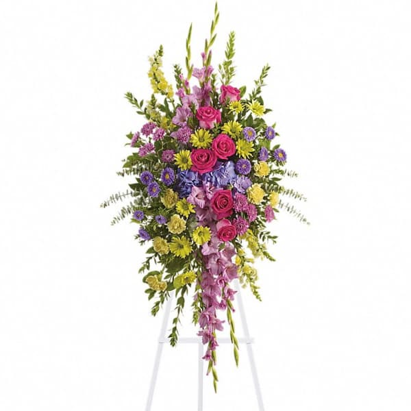 Tall standing spray of pink roses with yellow and purple flowers on a white easel