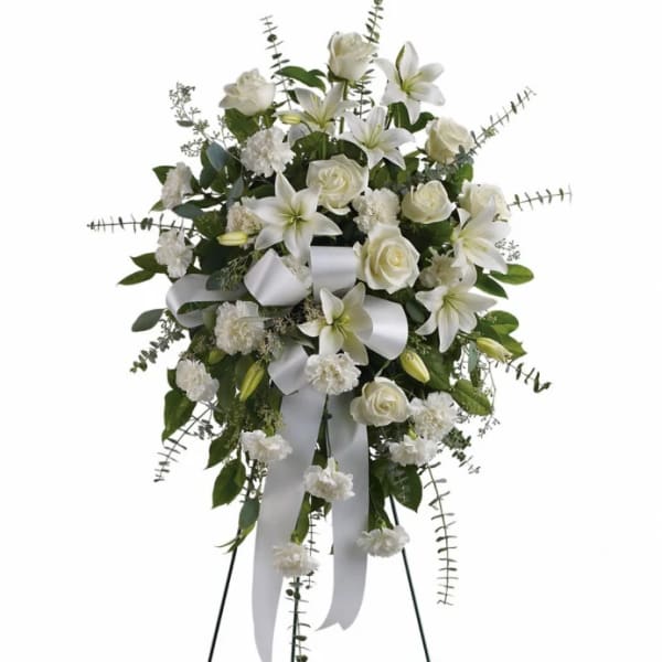 White floral standing spray with lilies, roses, and ribbon
