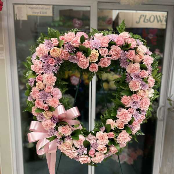 Heart-shaped floral wreath with pink roses, carnations, and lavender mums