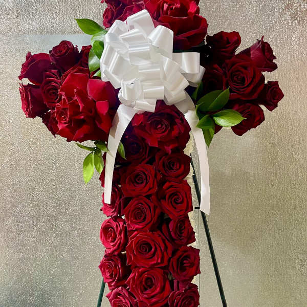Cross-shaped arrangement of red roses with a white bow