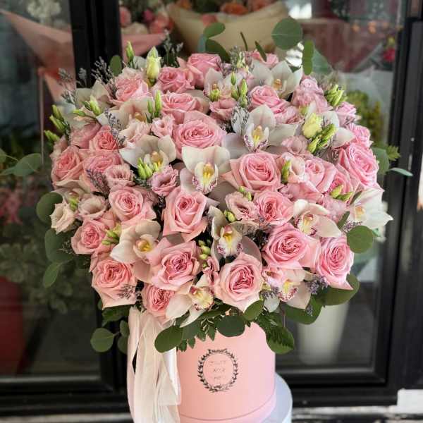 Pink roses and white orchids arranged in a pink hat box
