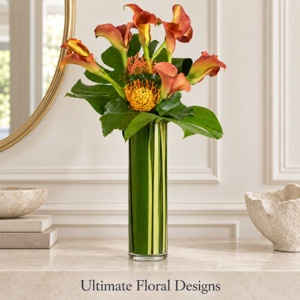 Orange calla lilies and pincushion blooms in a tall green vase