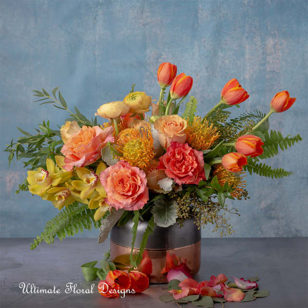 Mixed bouquet of tulips, roses, and orchids in a metallic vase
