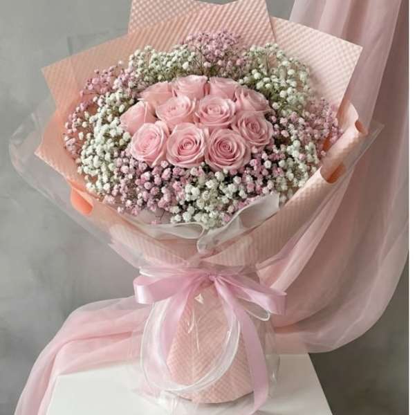 Pink rose bouquet wrapped in pastel paper with a ribbon
