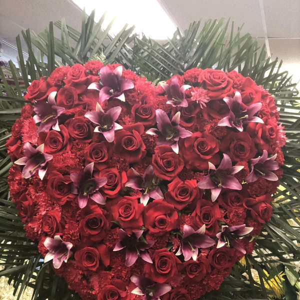 Heart-shaped arrangement of red roses and purple orchids