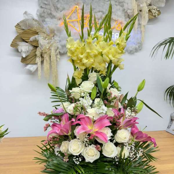 Tall floral arrangement with pink lilies, white roses, and yellow flowers
