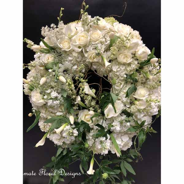 Large white floral wreath with roses, calla lilies, and greenery
