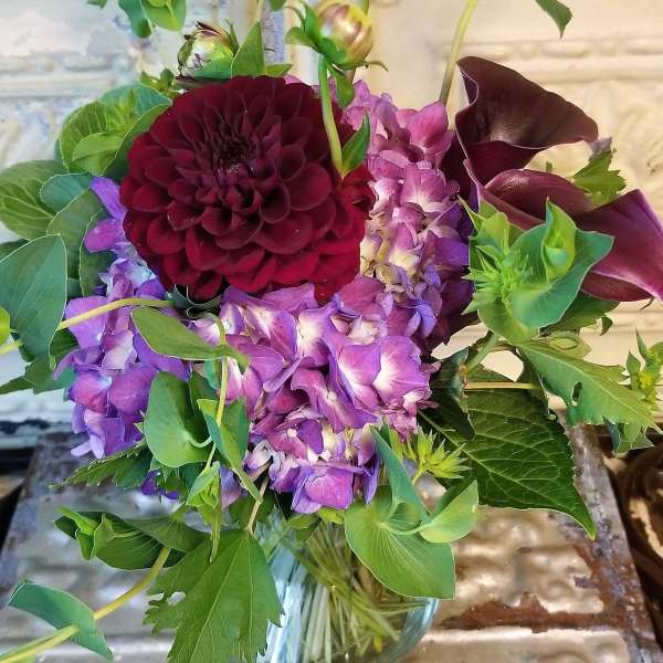 Bouquet of purple flowers with dark burgundy blooms in a glass vase