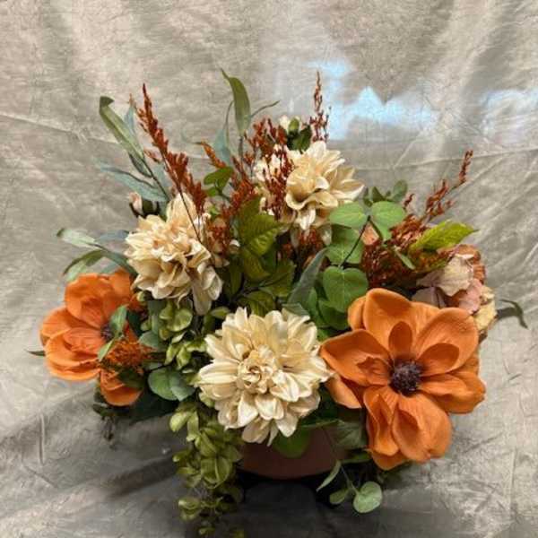 Orange and cream floral arrangement in a low container