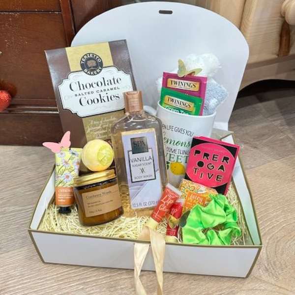 Gift box with cookies, tea, bath items, and a candle