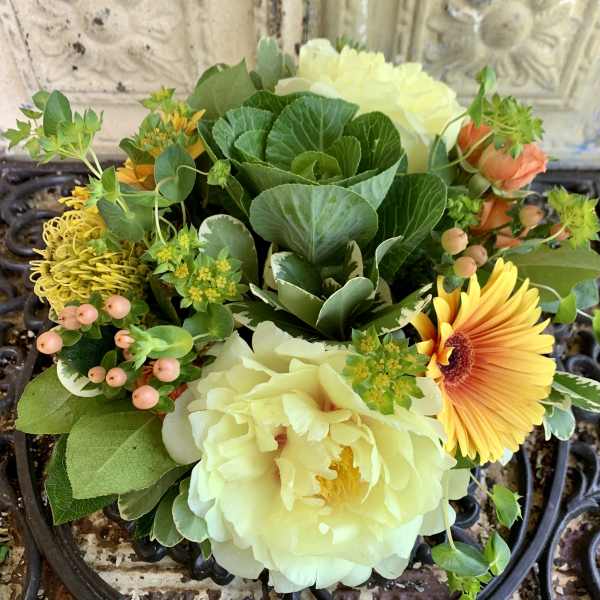 Mixed bouquet with pale yellow blooms, orange gerbera, and green foliage