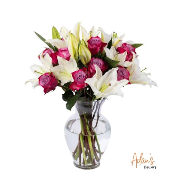 Pink roses and white lilies arranged in a clear glass vase