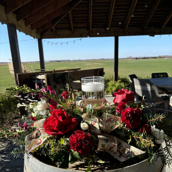 Red and white floral centerpiece with a glass candle on a barrel