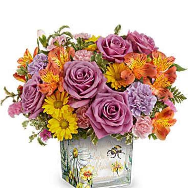 Square vase of purple roses with orange alstroemeria, yellow daisies, and pink blooms in a floral printed container