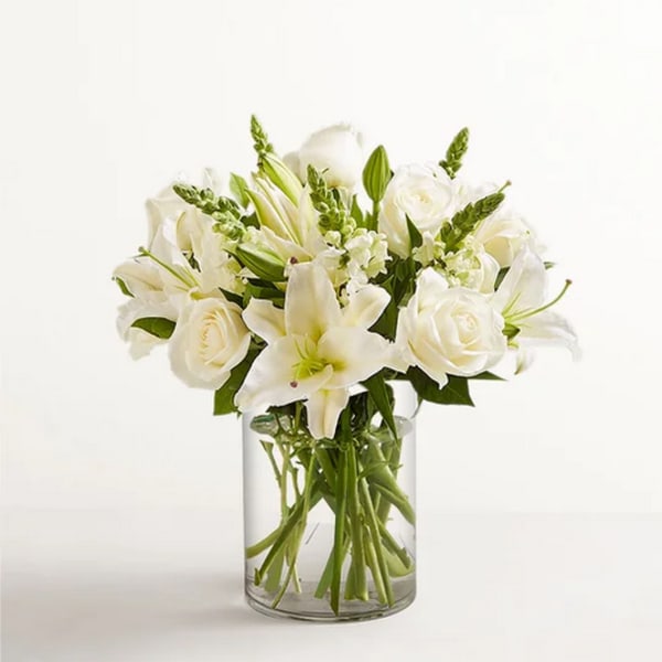 White lilies and roses arranged in a clear glass vase
