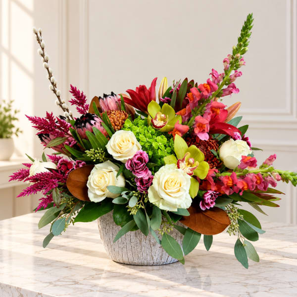 Mixed floral arrangement in a textured white vase with cream roses and bright pink blooms