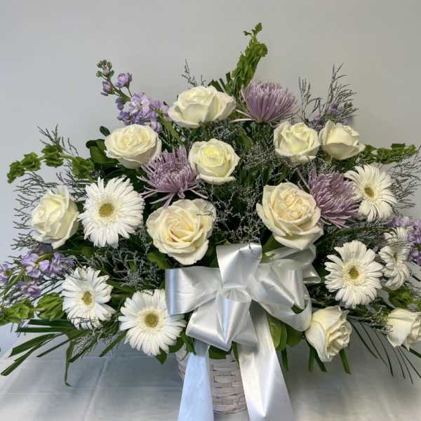 White roses and daisies in a white basket with a silver bow
