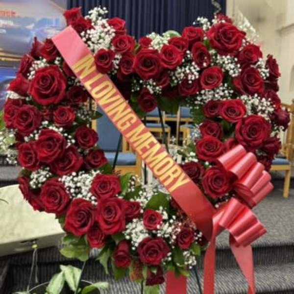 Heart-shaped wreath of red roses with white baby's breath and a memorial ribbon