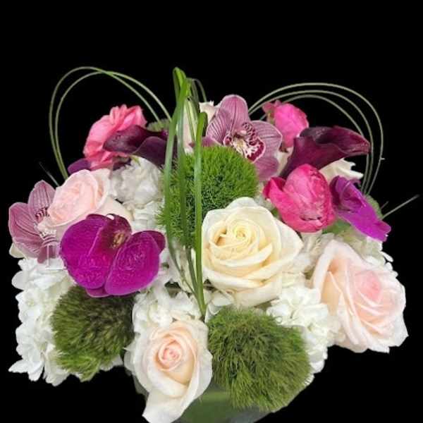 Mixed pink, white, and purple flowers in a glass vase