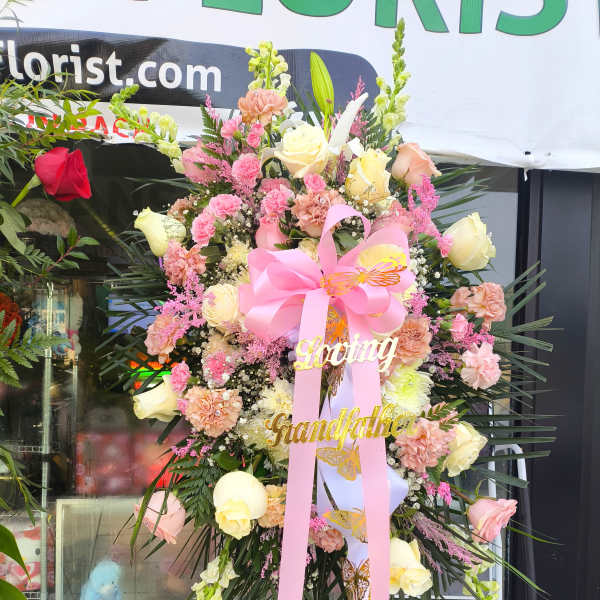 Large pink and cream floral standing spray with ribbon and name accents