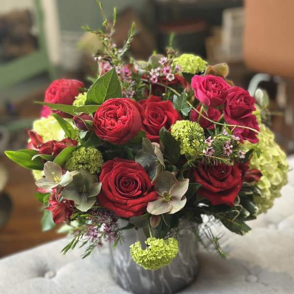 Round arrangement of red roses with green hydrangea in a gray marbled vase