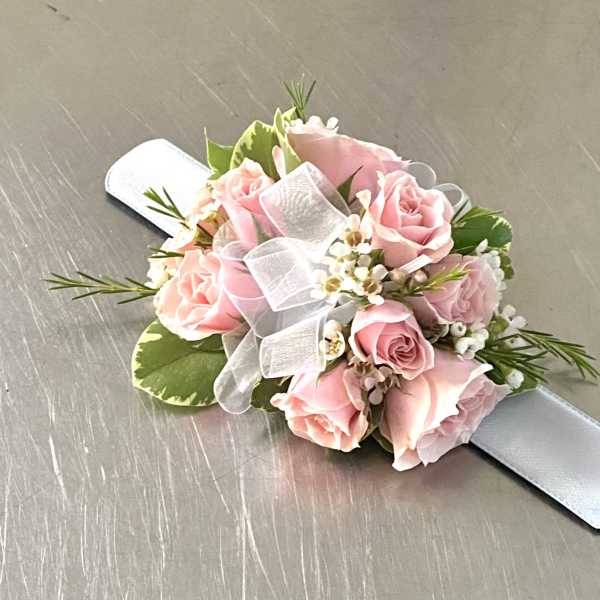 Pink rose wrist corsage with white ribbon on a satin band