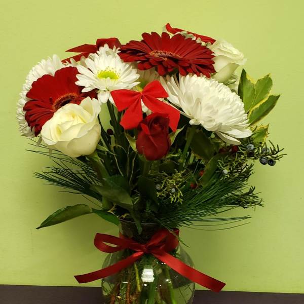 Bouquet of red and white flowers in a glass vase with a red ribbon