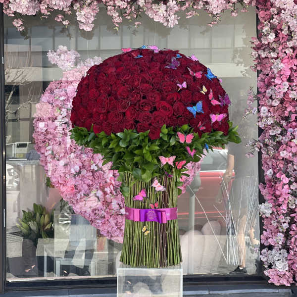Large bouquet of red roses with green foliage and butterfly accents