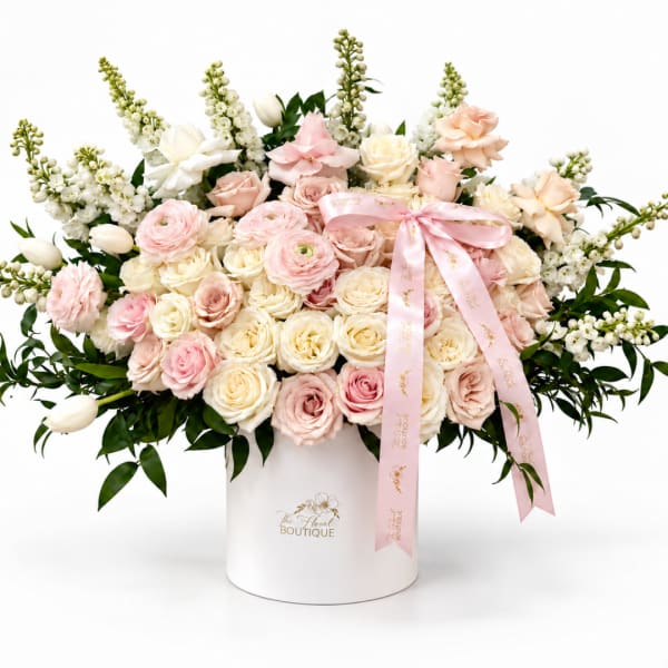 Large pastel bouquet of roses and ranunculus in a white hat box with pink ribbon
