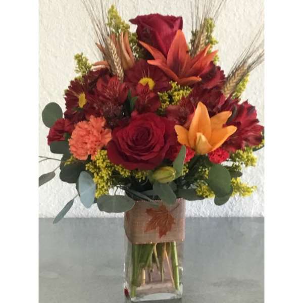 Red and orange mixed flower bouquet in a clear vase