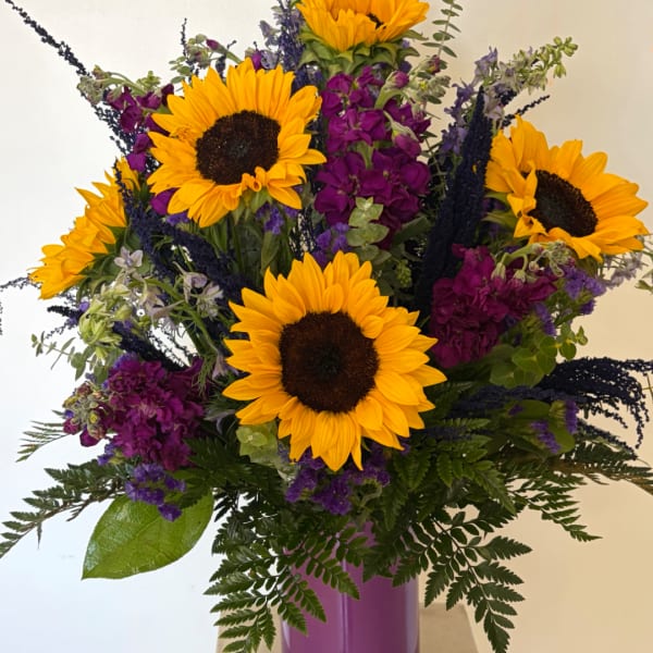 Bouquet of sunflowers and purple flowers in a purple vase