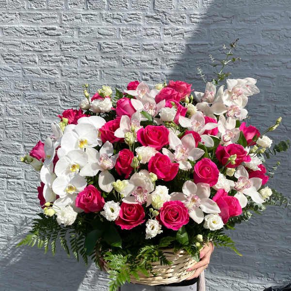 Basket arrangement of pink roses and white orchids