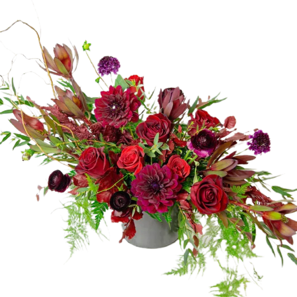 Red and burgundy floral arrangement in a gray vase