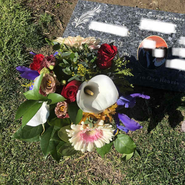 Bouquet of mixed flowers placed beside a gravestone