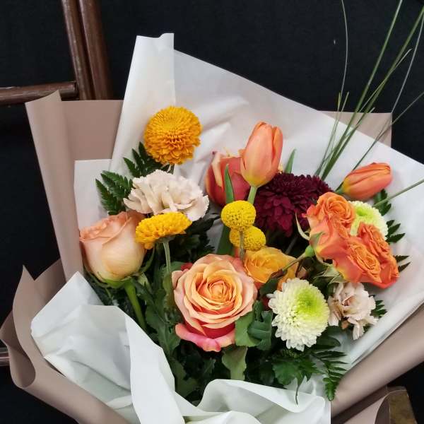 Bouquet of orange and peach roses with mixed chrysanthemums wrapped in white and taupe paper