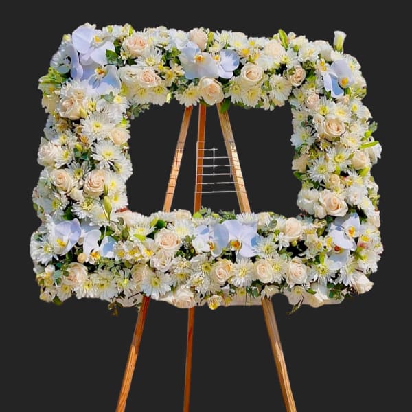 Square floral wreath on a wooden easel with white and blush flowers