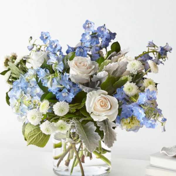 Blue and white bouquet of roses and mixed blooms in a glass vase