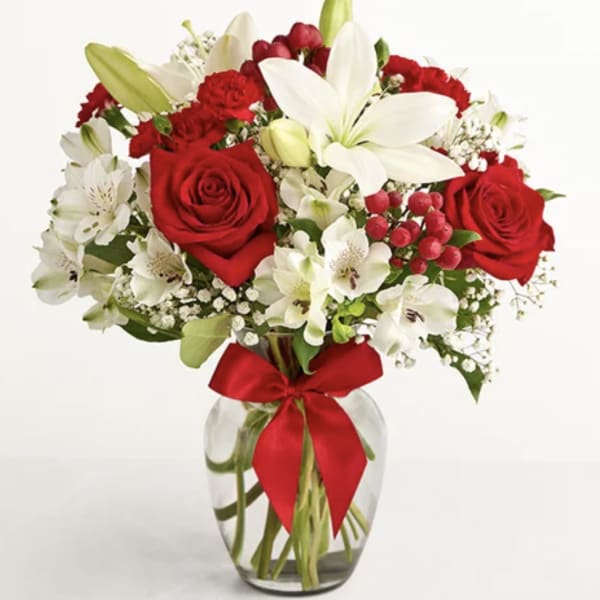 Red roses and white lilies in a glass vase with a red ribbon