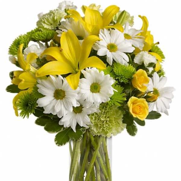 Yellow lilies and white daisies in a clear glass vase