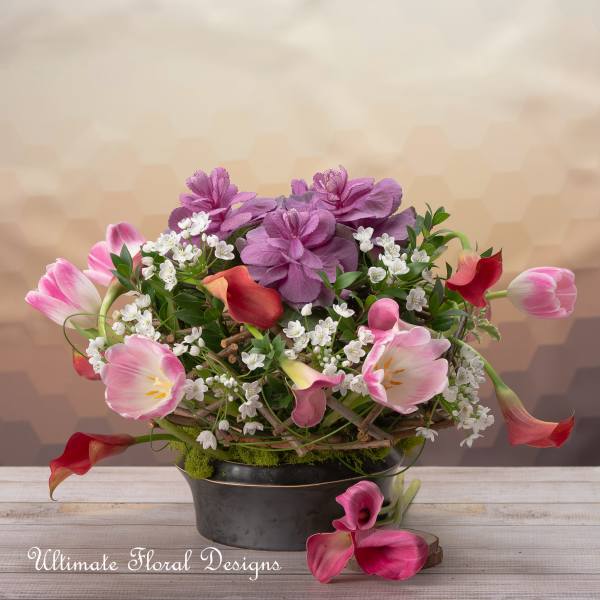 Pink tulips, calla lilies, and purple flowers in a black container