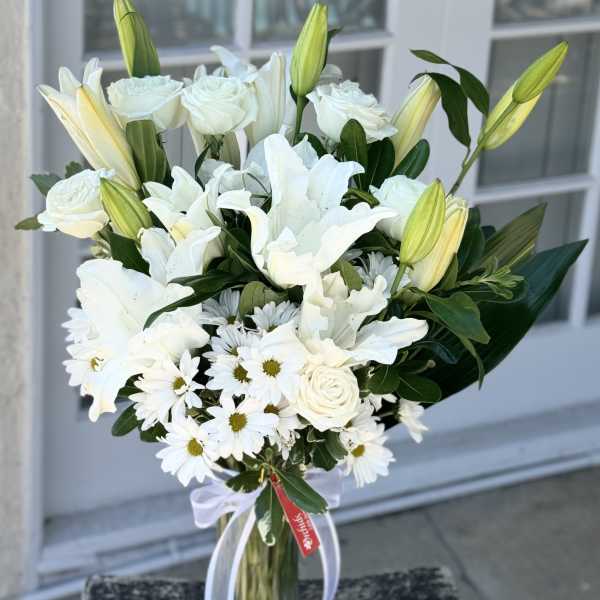 White lilies, roses, and daisies in a glass vase