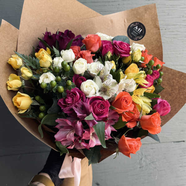 Mixed bouquet of colorful roses and alstroemeria wrapped in brown paper